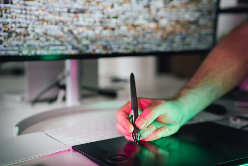 Hand drawing a product design on a graphics tablet with a monitor in the background