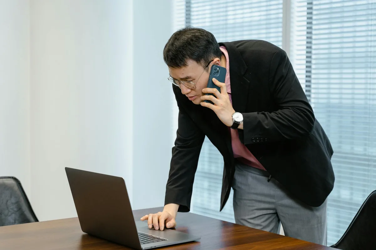Malaysian entrepreneur reviewing easystore pricing options on a phone at a home workspace