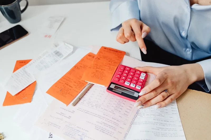 Businesswoman calculating expenses with a calculator and receipts