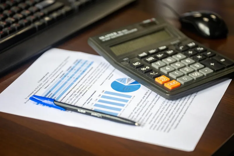 Desk with a calculator and financial report used to budget a Dubai business setup