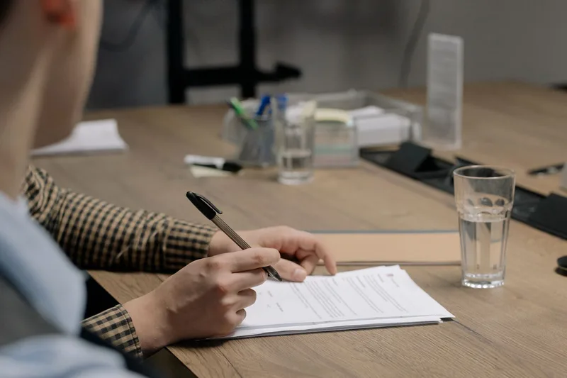 Person signing business license documents at a desk
