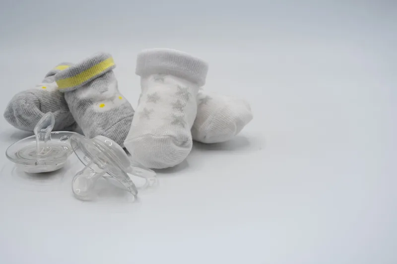Baby socks and pacifiers arranged for a product flatlay photograph