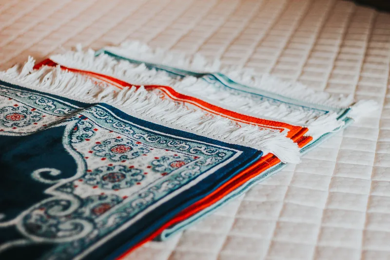 Sejadah dan kain solat pelbagai corak disusun kemas sebagai contoh produk pakaian solat untuk kedai online
