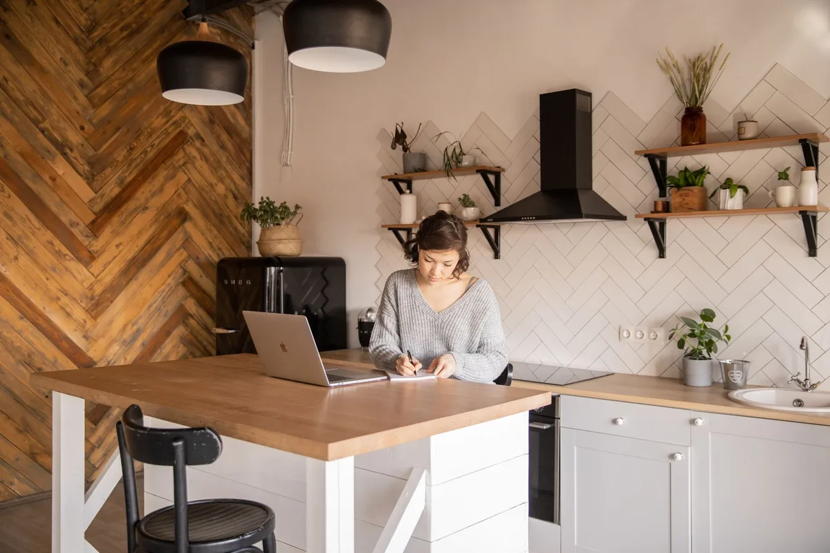 Usahawan Malaysia menyelidik idea niche produk di laptop dalam ruang kerja rumah yang terang