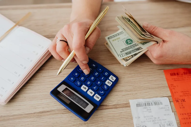 Calculating monthly business expenses with a calculator and receipts