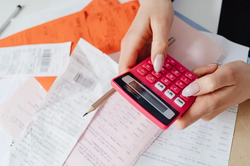 Hands using a calculator to work out fees and margins for a small online store