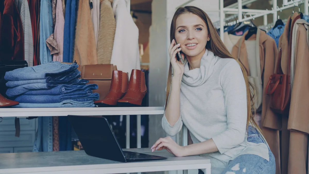 Online store owner working from her boutique with a laptop and phone